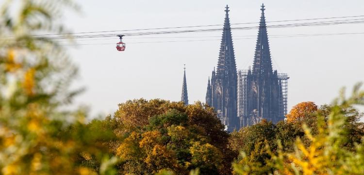 Rote Seilbahn in der Luft, dahinter der Kölner Dom
